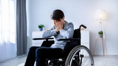 Engelli gençlerde depresyon. Tekerlekli sandalyedeki mutsuz engelli çocuk evde ağlıyor. Üzgün, çaresiz, yalnız, duygusal sorunları olan ergenler.