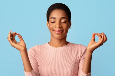 Harmony 'ye dikkat. Sakin Siyah Kadın Kapalı Gözlerle Meditasyon Yapıyor, Afro-Amerikan Bayan Yoga Yapıyor, Ellerini Mudra 'da Tutuyor, Mavi Arkaplanda İzole Edilmiş Duruyor,