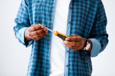 Beyaz stüdyo arka planında izole edilmiş plastik saplı plastik tornavida tutan tanınmayan siyah erkek el, mahsul, yakın çekim. Montaj için araçlar, aksesuarlar, mobilya montajı veya yenileme dairesi