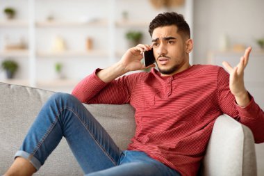 Sinirli Arap adam koltukta oturuyor, cep telefonuyla konuşuyor, fotokopi odasına bakıyor. Sinirli ortadoğulu genç adam akıllı telefondan konuşuyor, kız arkadaşı ya da müşteri hizmetleriyle kavga ediyor.