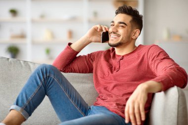 Mutlu, yakışıklı, orta doğulu adam rahat bir oturma odasında kanepede oturuyor, sevgilisiyle ya da arkadaşıyla cep telefonuyla konuşuyor, gülümsüyor ve fotokopi odasına bakıyor. İletişim konsepti