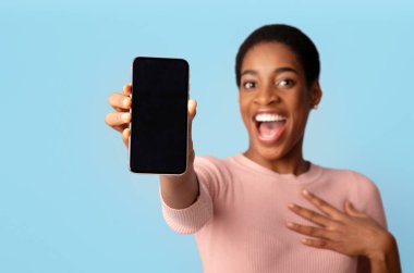 Harika bir uygulama. Boş Siyah Ekran ile Modern Akıllı Telefon Gösteren Harika Afrikalı Kadın, Mobil Uygulama Tasarımı veya Reklamları İçin Kopyalama Alanı Gösteriliyor, Mavi Arkaplan Üzerinde İzole Edilmiş, Model