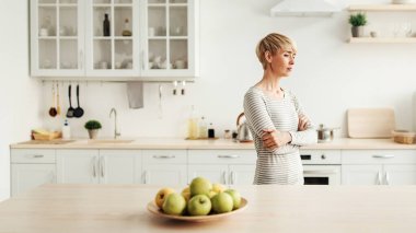 Kavga, ilişkilerde sorunlar, ayrılık, olumsuz duygular ve covid-19 salgını sırasında boşanma. Yalnız, üzgün yetişkin bir kadın. Kocası evden ayrıldıktan sonra mutfaktaki mutfaktaki üzgün kadın. Boşluğu taklit ediyor.