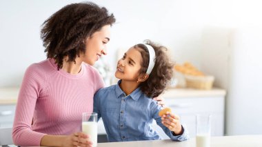 Mutlu bir ailenin portresi ya da birlikte kahvaltı yapması, küçük siyah bir kızın güzel bir kadını kucaklaması, bardaklarını tutması ve süt içmesi, ve birbirlerine bakmaları.