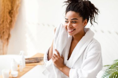 Yüz derisi. Çekici siyahi kadın, sabahları evdeki modern banyoda duran deriyi havluyla temizliyor. Dişi Güzellik Rutini Konsepti