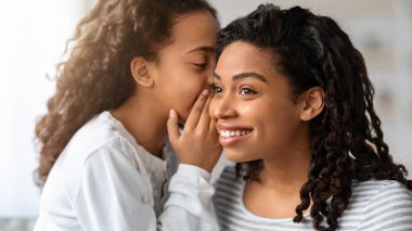 Zenci kız heyecanlı güzel annesine bir şeyler fısıldıyor, yakın plan bir portre. Afrikalı Amerikalı anne ve kızı evde birbirlerine bağlanırken sırlarını paylaşıyorlar. Annelik kavramı