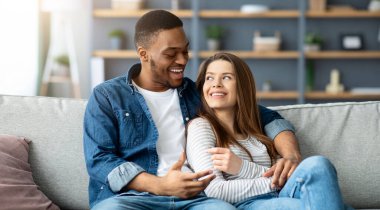 Yurt içi eğlence. Romantik, ırklar arası bir çift evde birlikte rahatlıyor, siyah ve beyaz kadınları seviyorlar, oturma odasında dinleniyorlar, birlikte vakit geçiriyorlar.