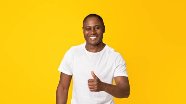 İyi şanslar, başarı, iyi ruh hali, onaylayın, iyi bir değerlendirme. Neşeli yetişkin özgüvenli Afrikalı Amerikalı adam servisi onaylıyor, başparmak işareti gösteriyor, turuncu arka planda izole edilmiş, stüdyo fotoğrafı.