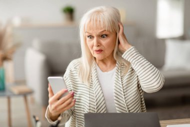 Oh hayır. Hayal kırıklığına uğramış orta yaşlı bir kadının portresi, cep telefonu ekranını tutmakta ve ona bakmakta, masa başında çalışmakta, şaşırmış bir kadının kafasını tutmakta,