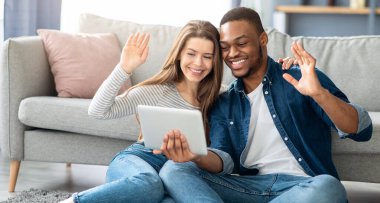 Video çağrısı. Arkadaşlarıyla internet konferansı için Dijital Tablet kullanan, Mutlu Irklar Arası Çiftler Gülümseyen, Webcam 'a el sallayan, Çevrimiçi İletişimin keyfini çıkaran,