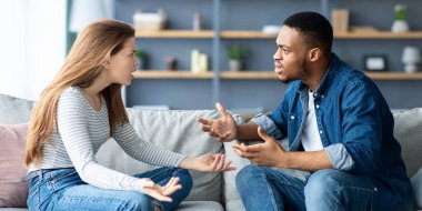 Karışık Çiftler Çatışması. Genç Irklar Arası Aşıklar evde tartışıyor, oturma odasında koltukta otururken birbirlerini suçluyorlar, siyah adam ve beyaz kadının ilişki sorunları var, boş alan var.