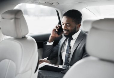 Gününü planlayan ve telefonla konuşan işadamı, ofise arabayla gidiyor