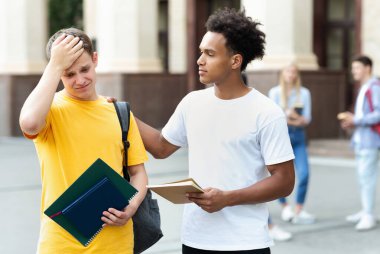 Başarısız test. Genç adam, kötü sınav sonucu arkadaşını teselli ediyor.