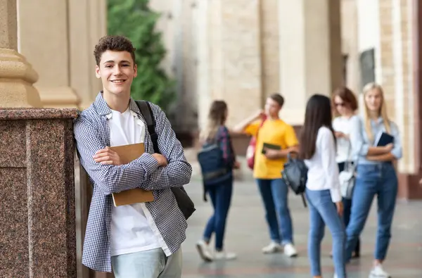 Üniversite hayatı. Mutlu adam kitap tutan ve gülümseyen, arkadaşlarına karşı duran