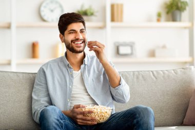 Doğulu rahat bir adam evde boş vakit geçiriyor, patlamış mısır yiyor ve televizyon seyrediyor. Heyecanlı Arap adam, oturma odasındaki kanepede dinlenirken sinemadan zevk alıyor.