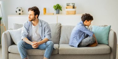 Aile sorunları konsepti. Sinirli baba oğluyla koltukta sırt sırta oturup tartıştıktan sonra birbirini görmezden geliyor. İnatçı baba ve çocuk çatışmadan sonra ne bakar ne de konuşur.