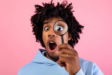 Pembe stüdyo arka planındaki büyüteçten bakan şoke olmuş genç adam. Bir şeyden şüphelenen, soruşturan ya da sorgulayan Afrikalı Amerikalı bir ergen. Sır, şüphe kavramı