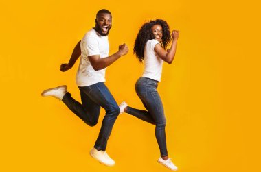 Neşeli Siyah Çift Havada Koşuyor, sarı arka planda eğleniyor