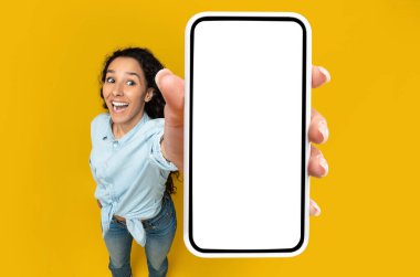 Bu harika uygulamayı kontrol et. Duygusal Kadın Elinde Büyük Beyaz Akıllı Telefon Ekranı Kameraya Yakın Görüntüleme, Turuncu Stüdyo Duvarında Uygulama Önerisi. Yüksek Açılı Üst Görünümün Üzerinde