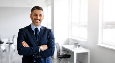 Resmi kıyafet müdürü kılığındaki mutlu orta yaşlı adam ofis içi kolları bağlı poz veriyor ve kamera, panorama ve fotokopi odasına gülümsüyor. Başarı, iş, girişimcilik hikayesi