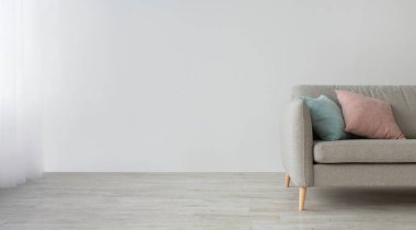 Evdeki oturma odasının içinde çok az. Yerde mavi ve pembe yastıklı gri kanepe, gün ışığında ışık perdeleri, ışık duvarı arka planında, düz döşeme, panorama, fotokopi odası, kırpılmış