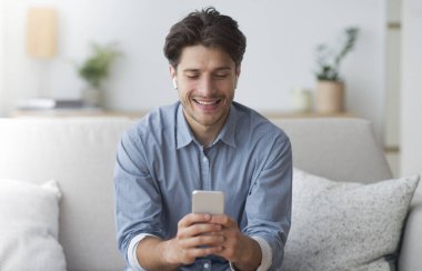 Mobil Oyunlar. Wirelss Kulaklıklı Neşeli Adam. Smatphone 'da oynuyor..