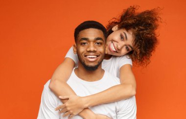 Aşk sarılma içinde genç Afro-Amerikan çift turuncu arka plan üzerinde poz alanı Kopyala