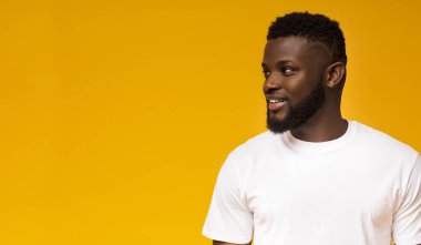 Yarı döndü gülümseyen afrikalı-amerikalı adam sarı stüdyo arka plan üzerinde kopya alanı bakarak