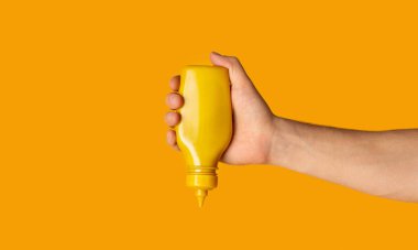 Turuncu arka planda hardallı erkek el sıkma şişesi, yakın çekim. Metin için boşluk