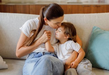 Annesini seven, küçük kızını kucaklayan, koltukta yan yana oturan, mutlu anne ve çocuk evde kaynaşan, anne ve çocuk, birlikte vakit geçiren...