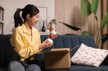 Mutlu Asyalı Bayan Tutucu Evde Oturan Başarılı Güzellik Dükkanı 'ndan sonra karton kutuları açan nemlendirici kavanozları teslim etti. Kozmetik Ürünleri, Teslimat Hizmeti Konsepti