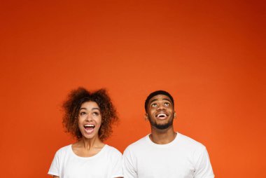 Yukarı doğru boş alan, turuncu studio arka plan Afro-Amerikan bin yıllık çift gülüyor