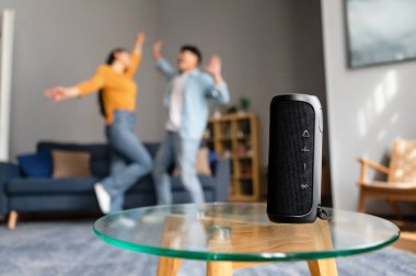En sevdiği müzik. Tanınmayan Asyalı çift, Song Via Wireless Smart Speaker dinleyerek Modern Ev İçi 'nde eğleniyor, zıplıyor ve dans ediyor. Seçici Odaklanma Müzikal Sütun