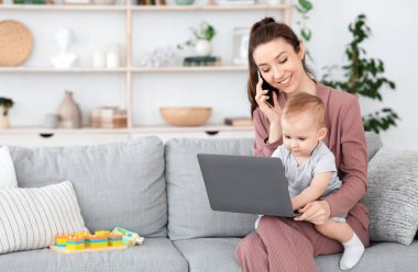 Bebekle çalışmak. Genç anne kucağında dizüstü bilgisayarla yazarken cep telefonuyla konuşuyor.