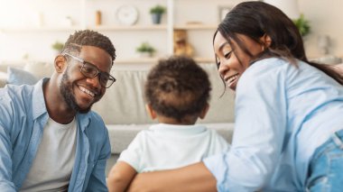 Aile bağı. Mutlu Milenyum Ebeveynleri Bebek Yürüyen Çocukla Oynuyor, Evde Küçük Oğluyla Zaman Geçiriyorlar, Yerde Oturuyorlar. Çocuk Bakımı, Sevimli Ebeveynlik Anları, Ebeveynlik Mutluluğu