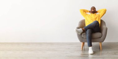 Tembel hafta sonu. Afrikalı Amerikalı Adam, gözleri kapalı, elleri başının arkasında oturan gri kapüşonlu, sarı kapüşonlu. Rahatlama ve Rahatlık Konsepti