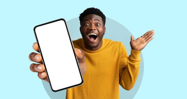 Parlak bir kazak giyen bir adam boş bir akıllı telefonu zevkle tutar, heyecan ve nişanı ifade eder. Arkaplan canlı bir mavi, sahnenin canlı atmosferine ekleniyor..