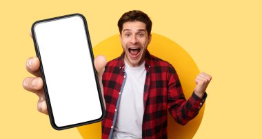 Kocaman gülümseyen genç bir adam elinde boş bir ekranla akıllı bir telefon tutuyor, neşe ve heyecan ifade ediyor. Arka plan canlı bir sarı, sahneye enerji katıyor..