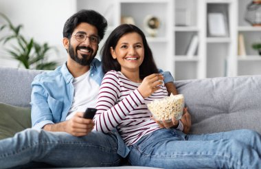 Mutlu, genç, çok kültürlü çift sakallı Arap adam ve güzel Hintli kadın kanepede oturur, kucaklaşır, birlikte televizyon izler, patlamış mısır yer, fotokopi çekerler. Ev eğlencesi