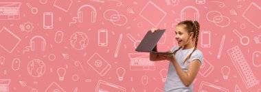 Okulun renkli temalı kolajıyla çevrili bir çocuk heyecanlı bir şekilde dizüstü bilgisayar tutuyor. Arkaplanda okulla ilgili çeşitli simgeler var, canlı ve çekici bir atmosfer yaratıyorlar..