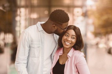 Sevgi, ilgi, tatil kavramı. Modern şehir dükkanının yakınında sevgilisini bir sürü renkli paketle öpen binlerce yıllık mutlu Afro-Amerikan adamın portresi sokakta yürüyordu.