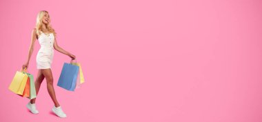 Hafta sonu alışverişi. Moda kıyafetli, beyaz spor ayakkabılı, alışveriş poşetleriyle yürüyen, pembe stüdyo arka planında izole edilmiş bedava fotokopi alanına bakan mutlu sarışın bir kadın.