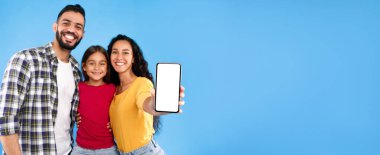 Bu Uygulamayı Kontrol Et. Arap Ailesi, Mavi Arkaplan Üzerindeki Stüdyoda Cep Telefonu Boş Ekranı Mobil Reklam Uygulaması Pozisyonuna Gösteriyor. Teknoloji, İnsanlar ve Gadget 'lar. Model