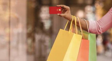 Kolay Ödeme Konsepti. Kredi kartı gösteren, alışveriş merkezinden parlak renkli alışveriş torbaları taşıyan, dışarıda dikilen, ücretsiz fotokopi alanı olan tanınmamış siyah kadının yakın çekimi. Perakende ve Satın Al