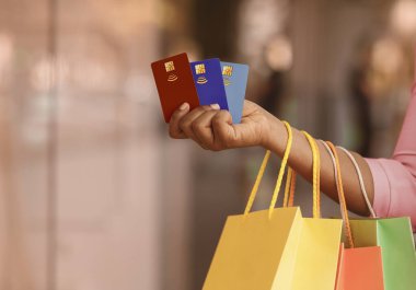 Satışlar ve İndirimler, Kolay Ödeme. Siyah Kadın Alışveriş Komitesi Renkli Alışveriş Torbaları ve 3 Borç Kredi Kartı, Mağaza Penceresinin yanında duran Bayan Kesilmiş, Bulanık Arkaplan, Kopya Boşluğu