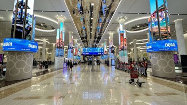 DUBAI, UNITED ARAB EMIRATES.15 SEPTEMBER 2023. Long, bustling airport corridor in Dubai filled with large information screens clipart