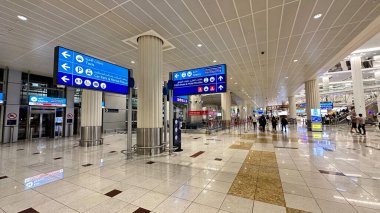 İnsanlar Dubai Havalimanı 'nın canlı ortamında gezinirken bir hareket senfonisi.