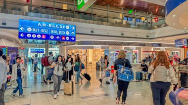 Dubai, BAE. 16 Eylül 2023 'te. Gezginlerin havaalanından çok yönlü hızla geçerek gümrüksüz büfeleri hızla geçtikleri hareketli bir sahne başlıyor.
