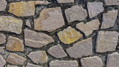 Kalıplı taş duvarın yakın çekimi, karmaşık desenler ve toprak renkler gösteriyor.