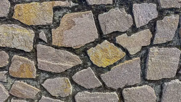 Kalıplı taş duvarın yakın çekimi, karmaşık desenler ve toprak renkler gösteriyor.